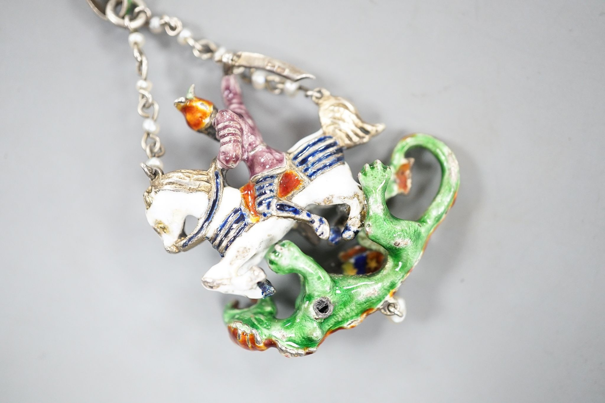 A 19th century Austro-Hungarian? gilt white metal, polychrome enamel, seed pearl and gem set 'St George & The Dragon' drop pendant, 4cm.